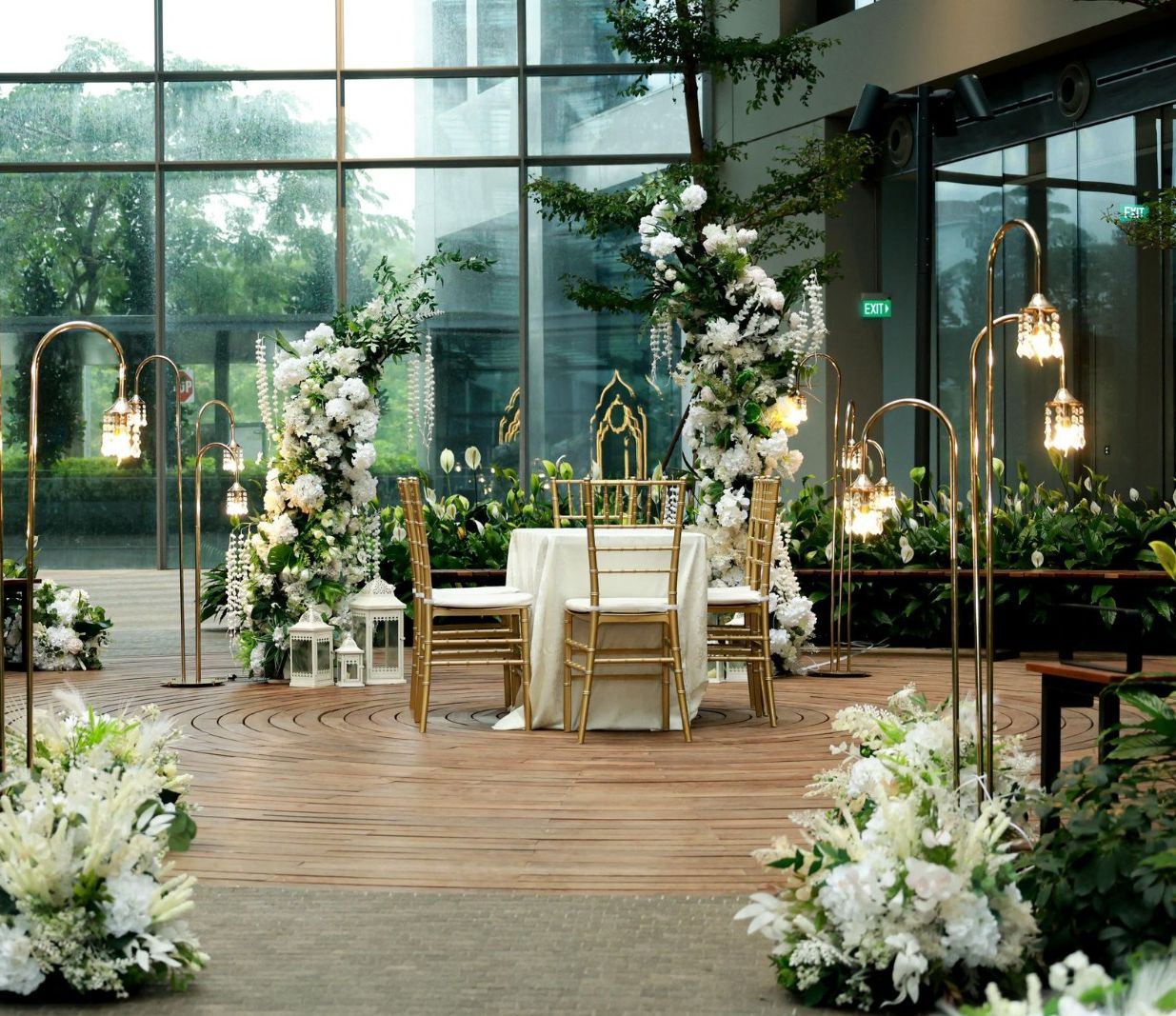 White floral ceremony setup beside tall windows at GEM Grand Ballroom