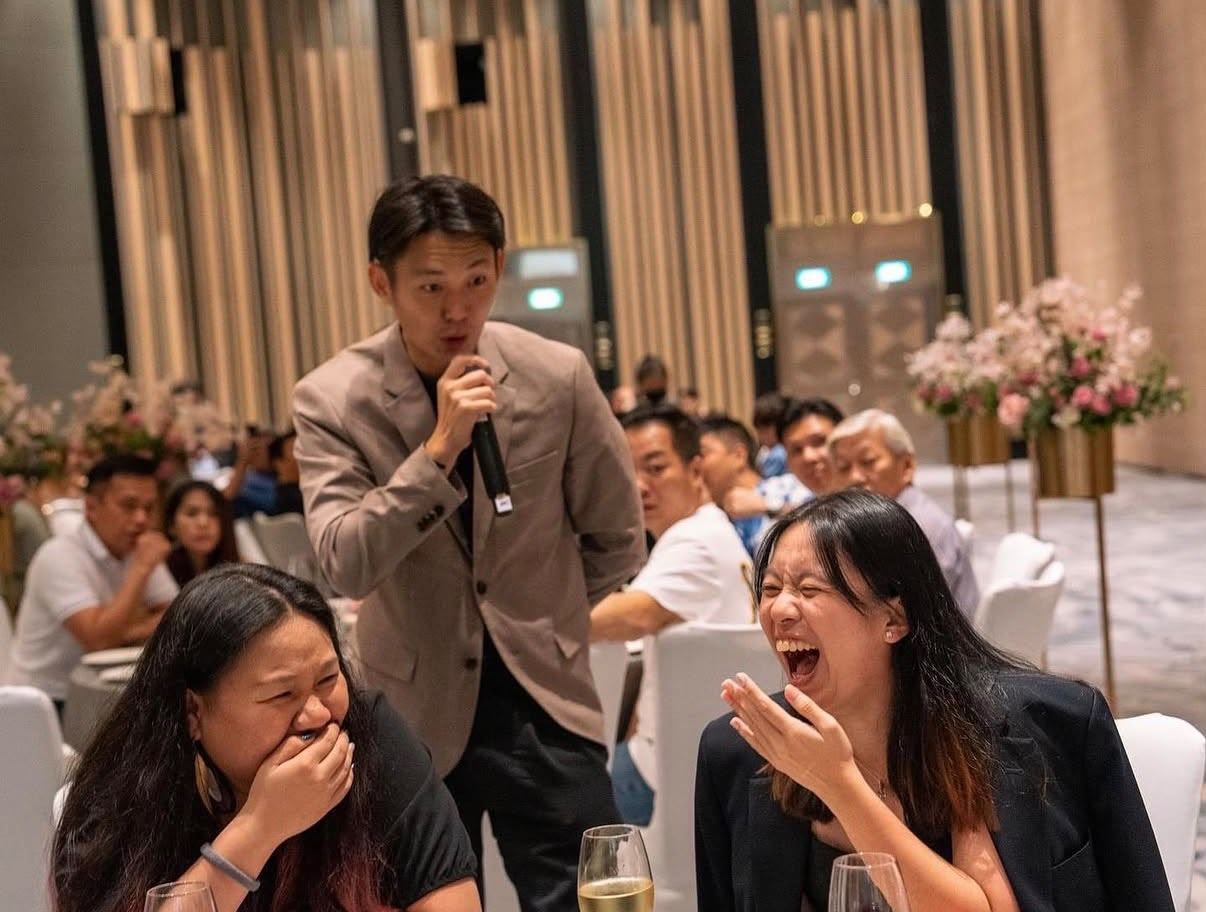 Emcee JonTee engaging laughing wedding guests at their table