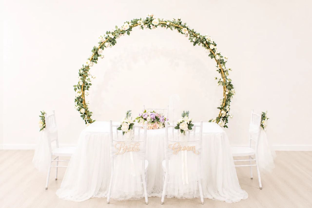 Full floral round arch behind a white solemnisation table