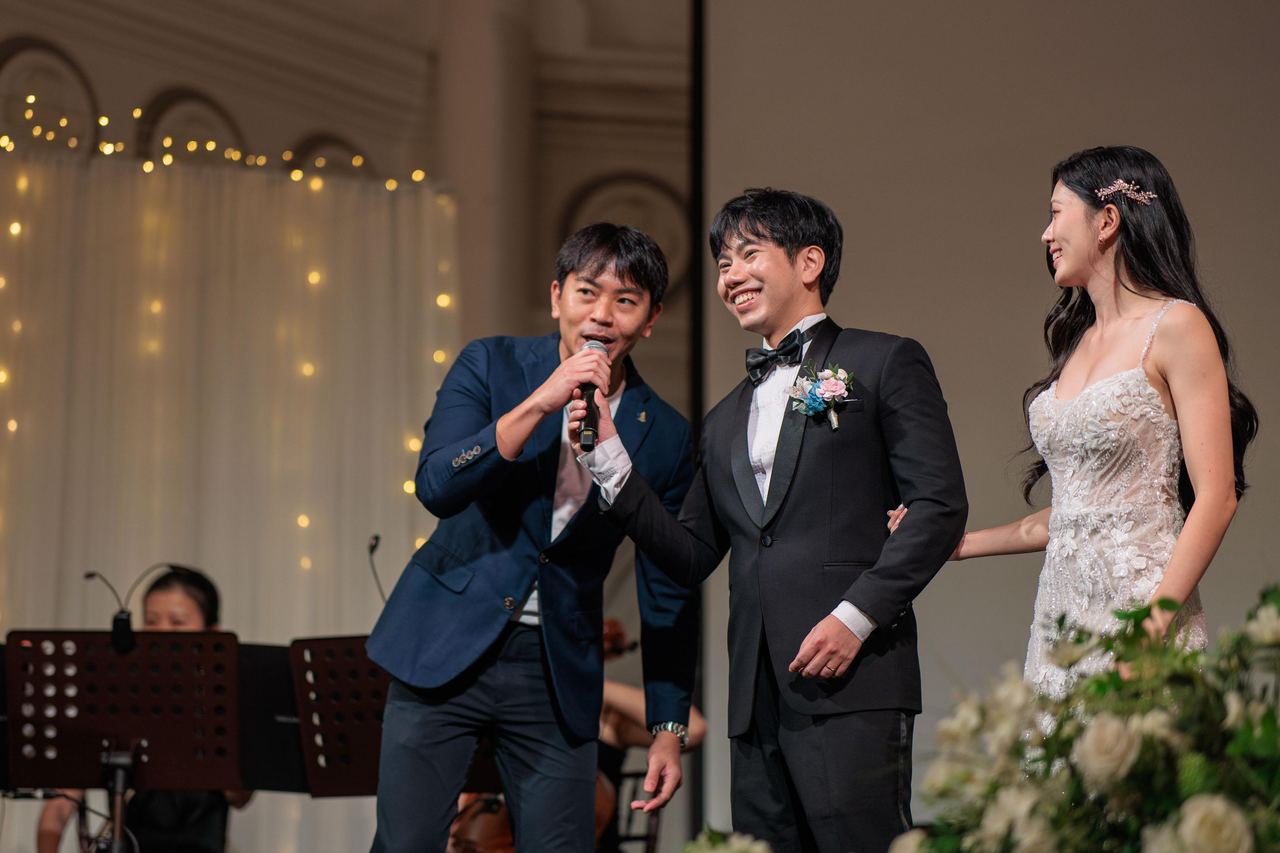 Emcee Rayson hosting on stage with the wedding couple