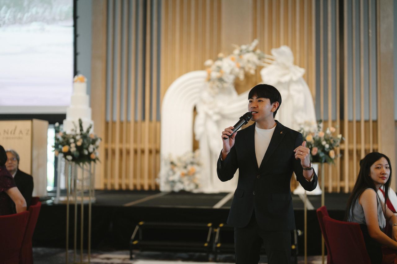Emcee Rayson hosting in front of a wedding stage