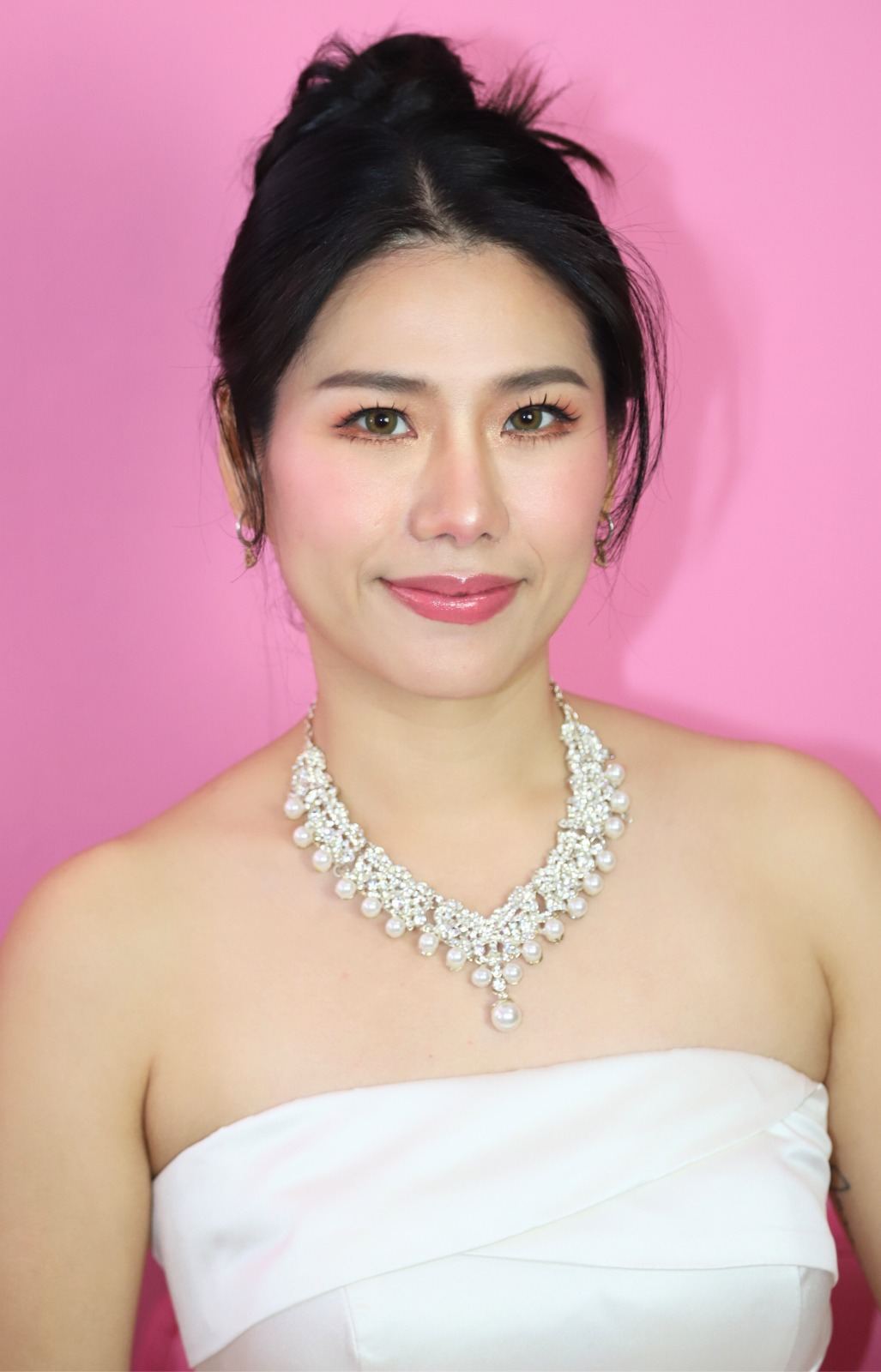 Bridal makeup portrait against a pink backdrop