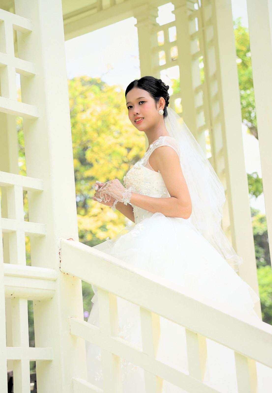 Bride in a white gown on a white pavilion staircase