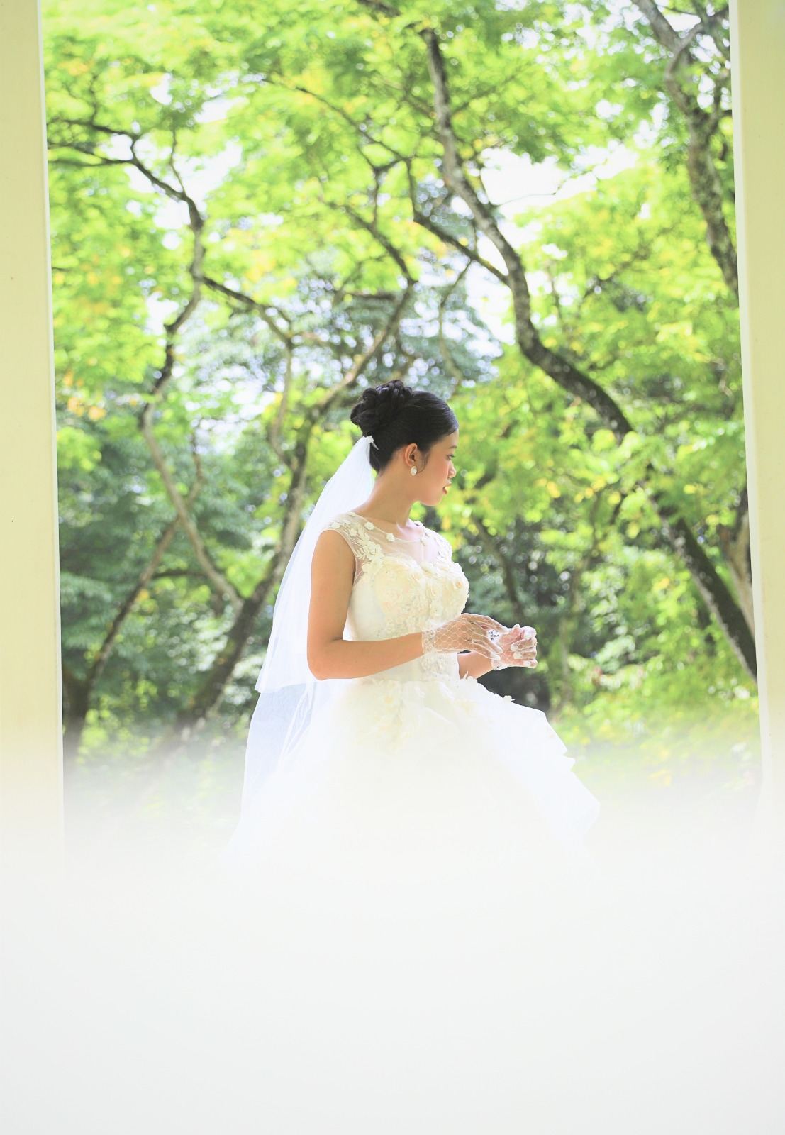Bride in a white gown framed by a pavilion and greenery