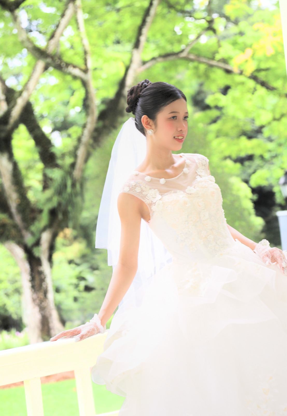 Bride posing beside a white railing in a garden
