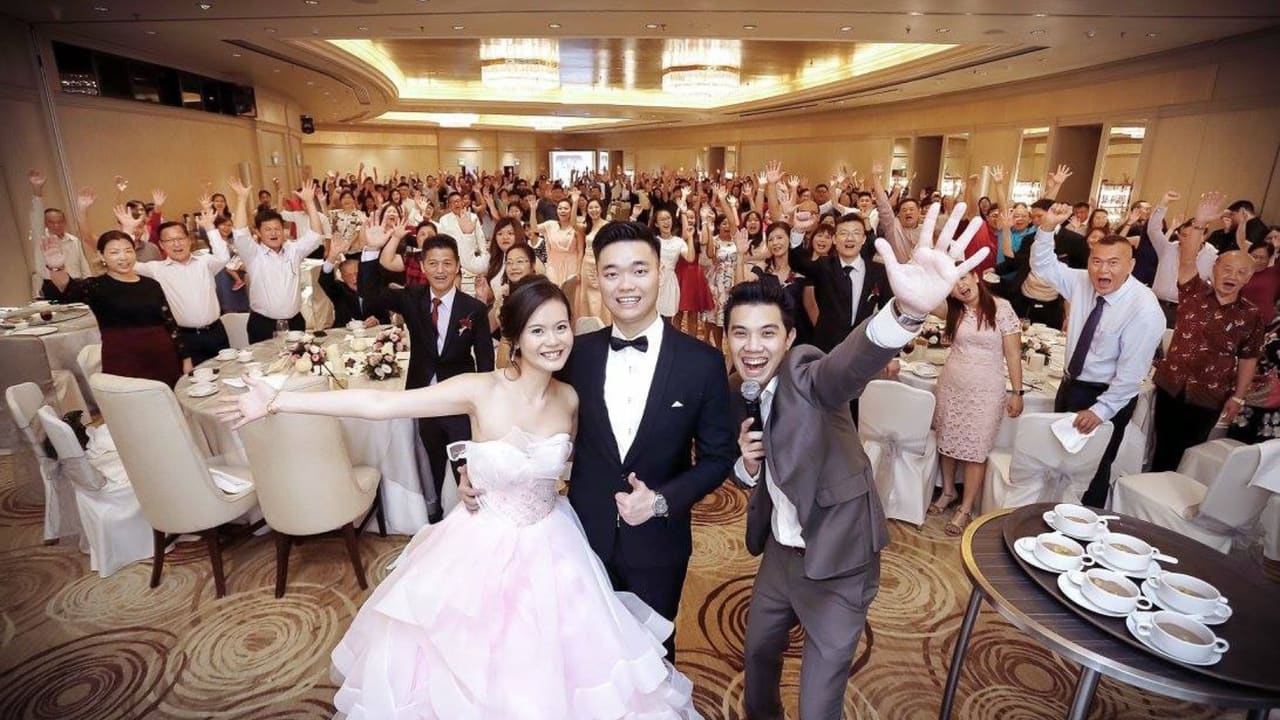 Emcee Stanley celebrating with a newlywed couple and wedding guests at a banquet