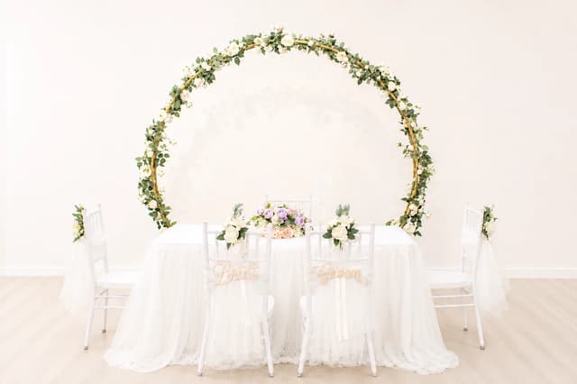 Full floral round arch behind a white solemnisation table
