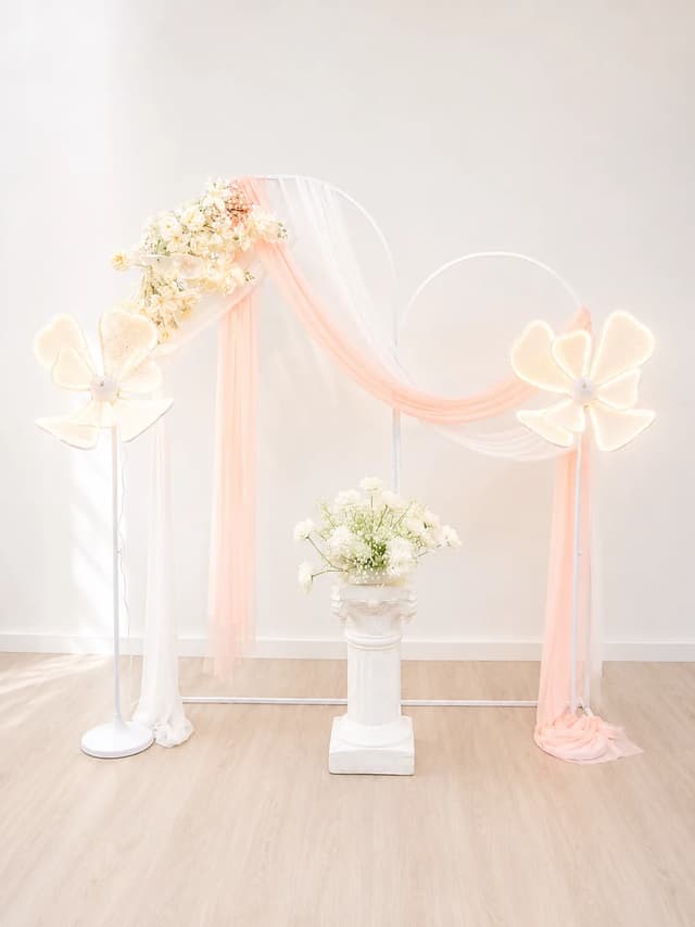Pastel draped dual arches with floral lights and Roman pillar