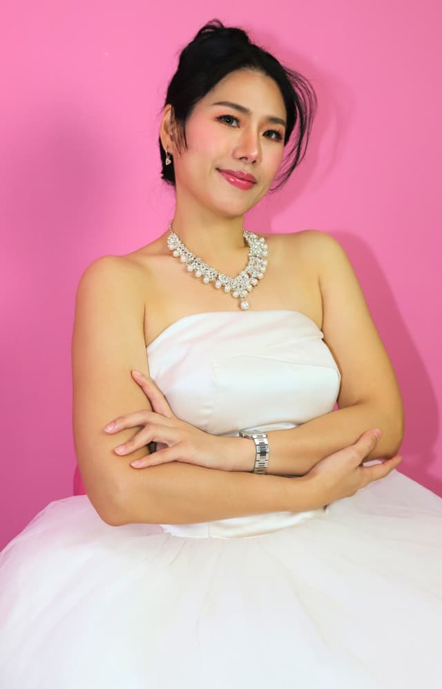 Bride posing in a white gown against a pink backdrop