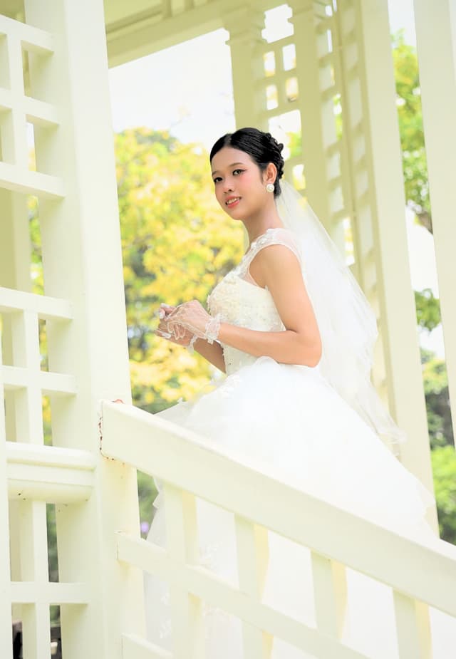 Bride in a white gown on a white pavilion staircase