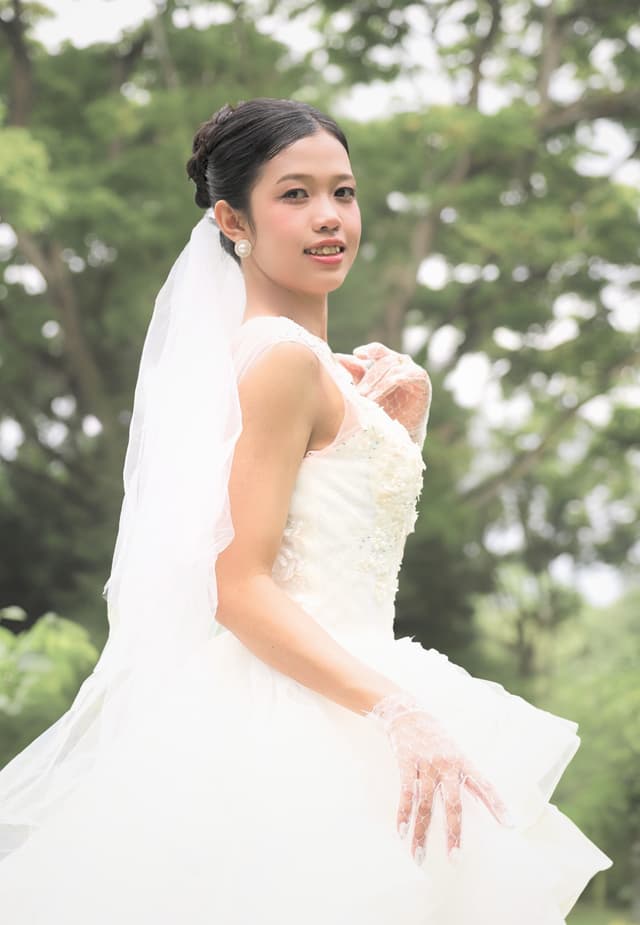 Bride posing outdoors in a white gown and veil