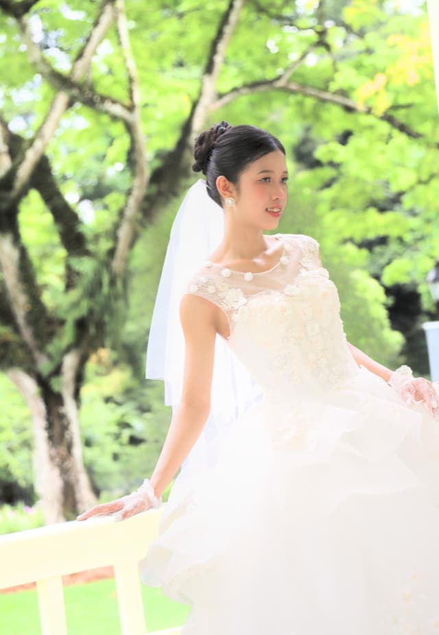 Bride posing beside a white railing in a garden