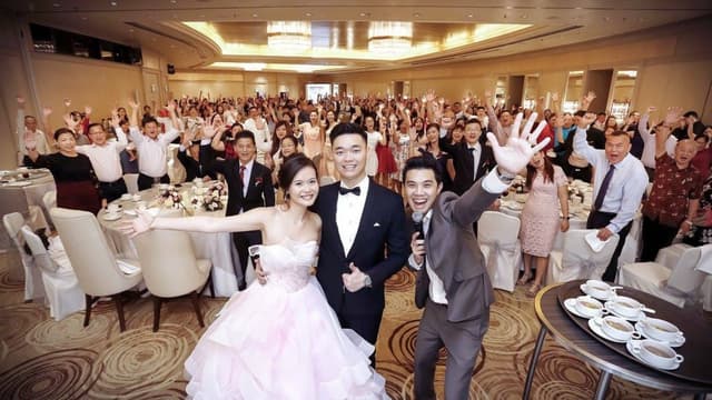 Emcee Stanley celebrating with a newlywed couple and wedding guests at a banquet